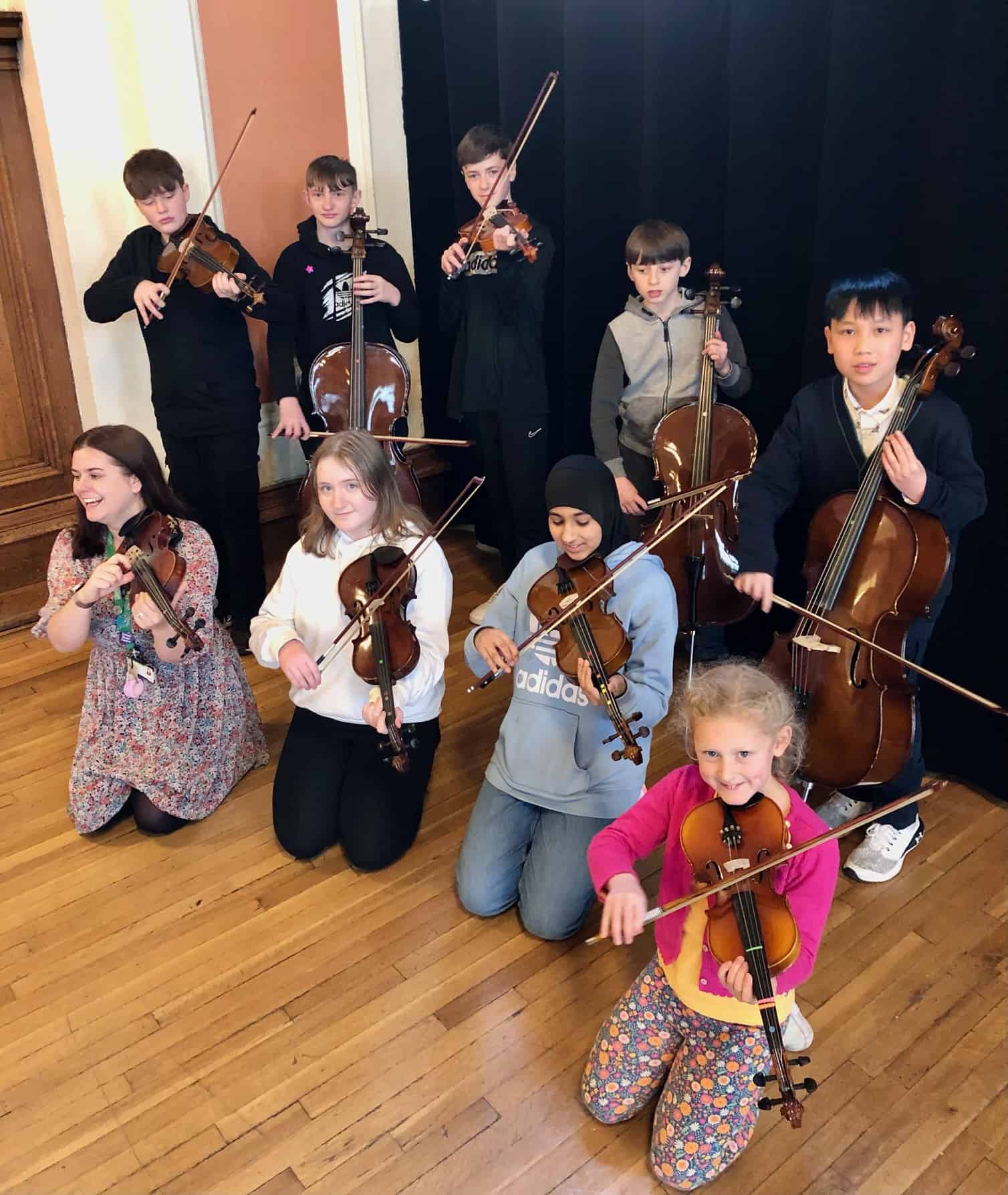 Students and staff from Laurus Cheadle Hulme hold their string instruments at the Benedetti Strings day at Stockport Town Hall.