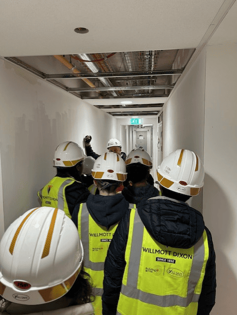 A group of students from Laurus Cheadle Hulme wearing protective gear as they walk through the Willmott Dixon construction site.