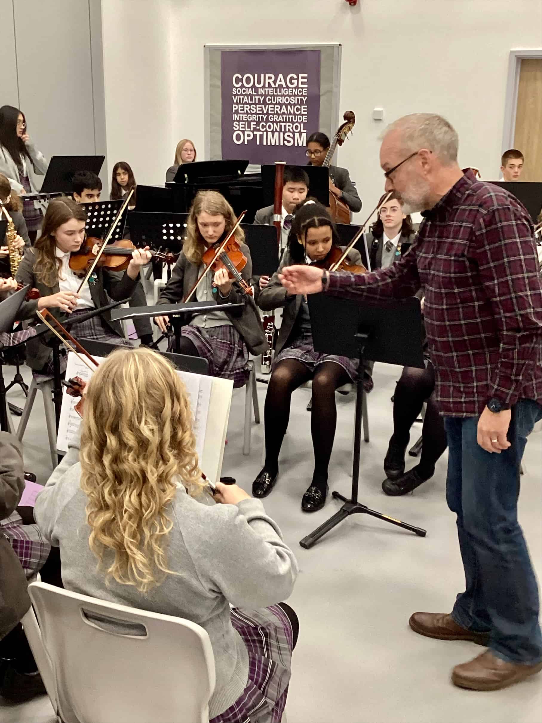 Students from the Laurus Cheadle Hulme Orchestra play their instruments, as David Hext conducts.